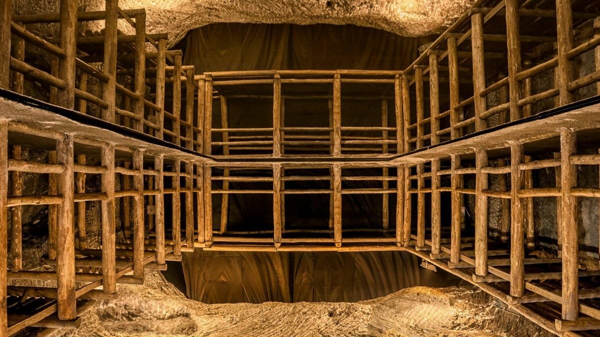 Intricate wooden scaffolding structure inside a well-lit underground cave or mine shaft.
