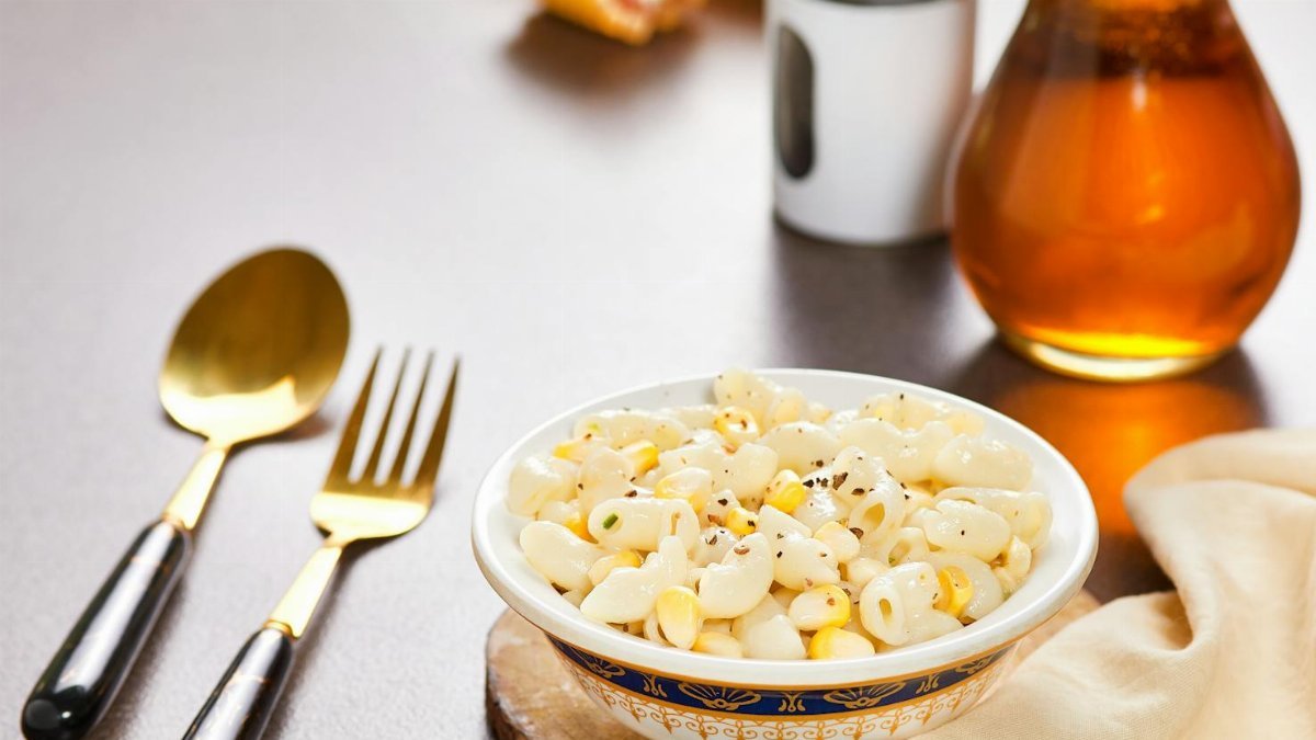Delicious creamy macaroni with corn and spices, captured on a rustic wooden background.