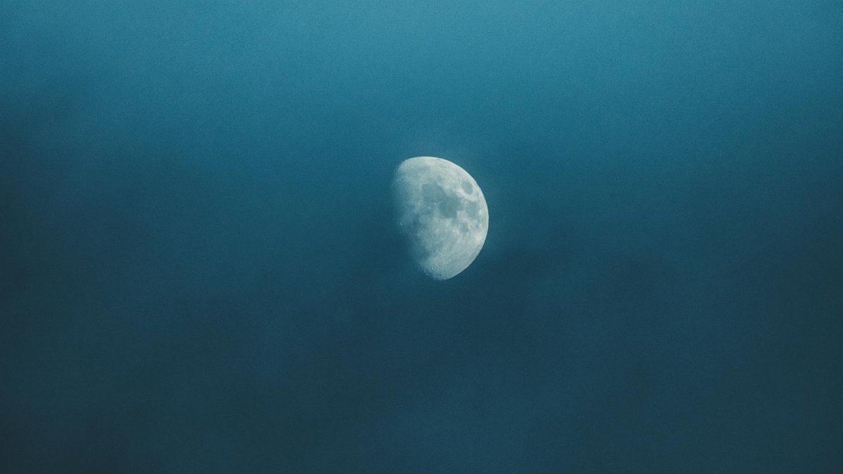 Waxing white moon with gray spots illuminating on foggy sky at bright night