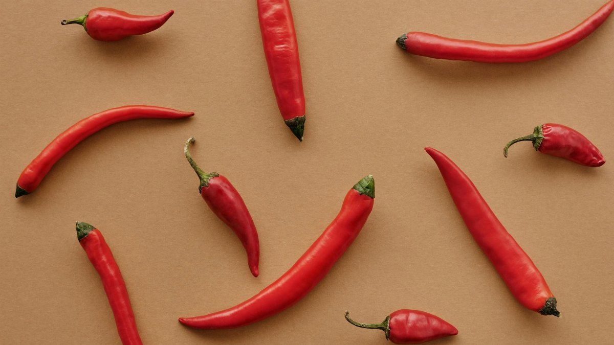 Flat lay of red chili peppers arranged on a brown textured background, showcasing vibrant color contrast.