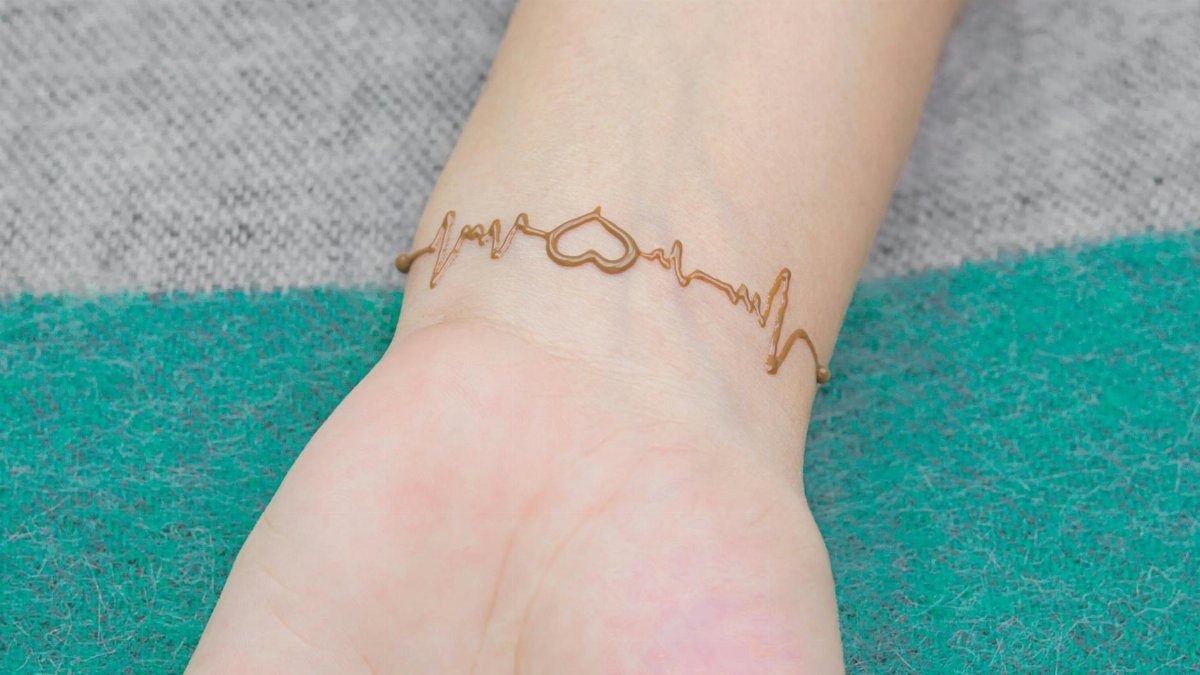 Close-up of an artistic heartbeat henna tattoo design on a person's wrist, showcasing creativity.