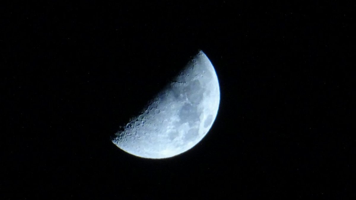 Stunning half moon cratered surface against a dark night backdrop.