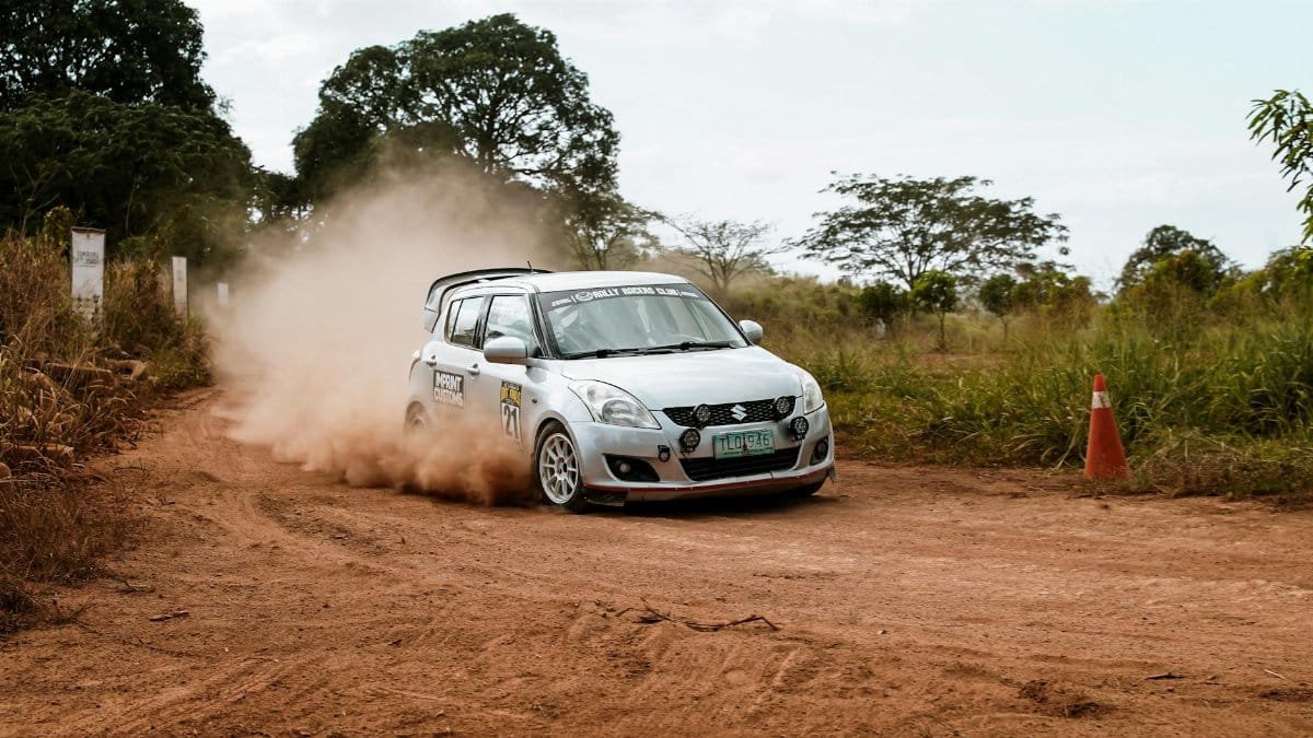 Exciting off-road rally car navigating a dusty track with skill and speed under clear skies.