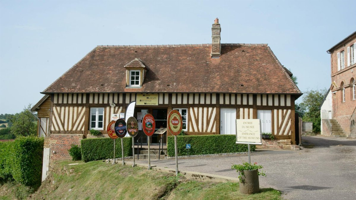 Charming traditional house in Camembert, Normandy, France, featuring unique half-timbered architecture and museum signs.