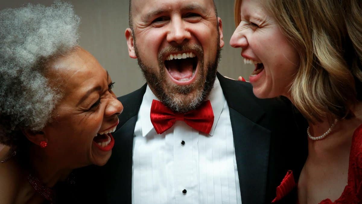A joyous group of friends laughing together at a formal event in Louisville.