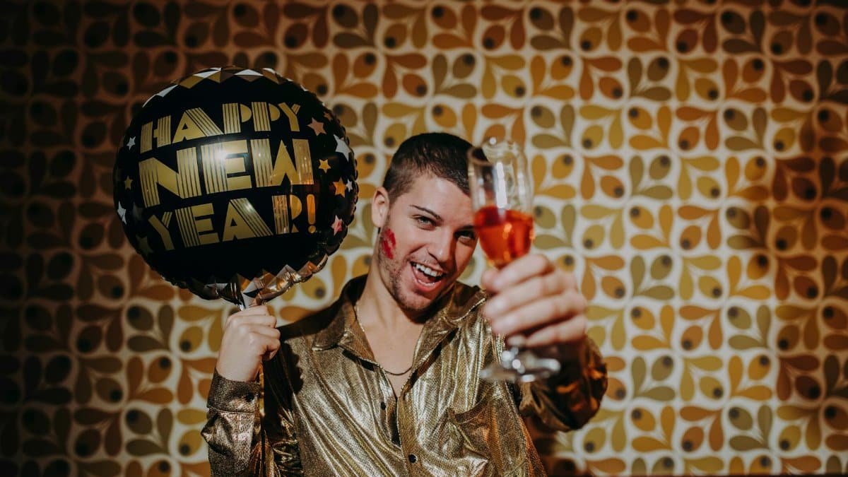 Man celebrating New Year's Eve with a balloon and champagne, capturing festive vibes indoors.