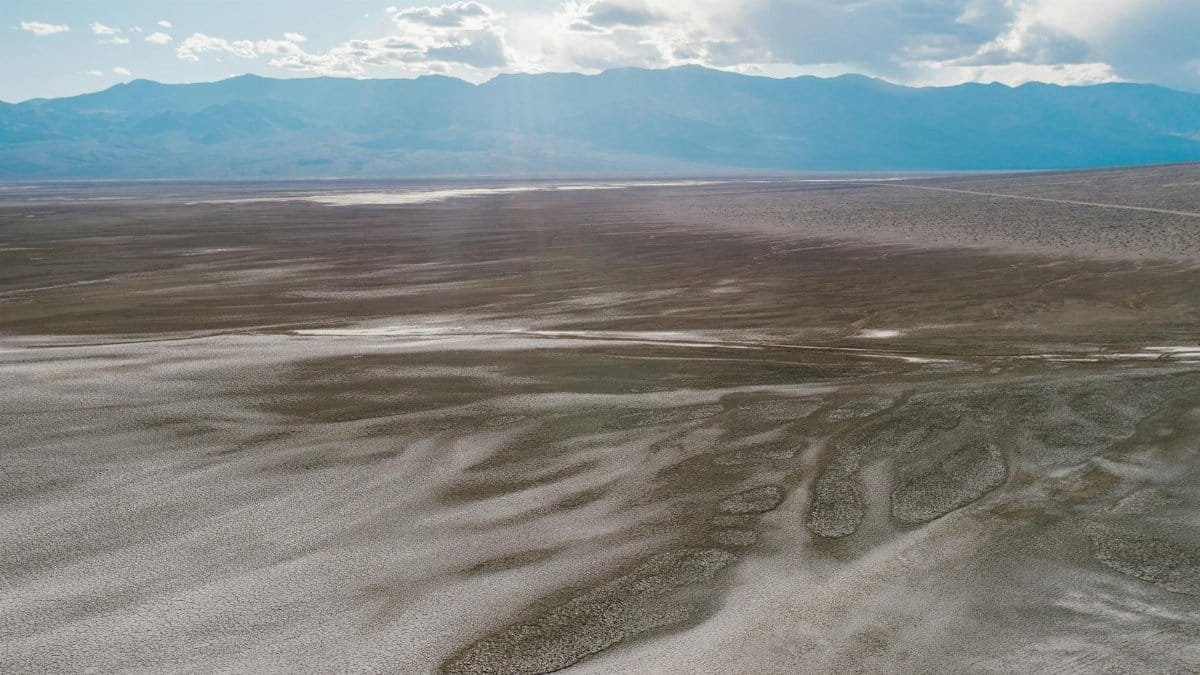 Panoramic view of Death Valley's arid landscape and distant mountains under a bright sky.