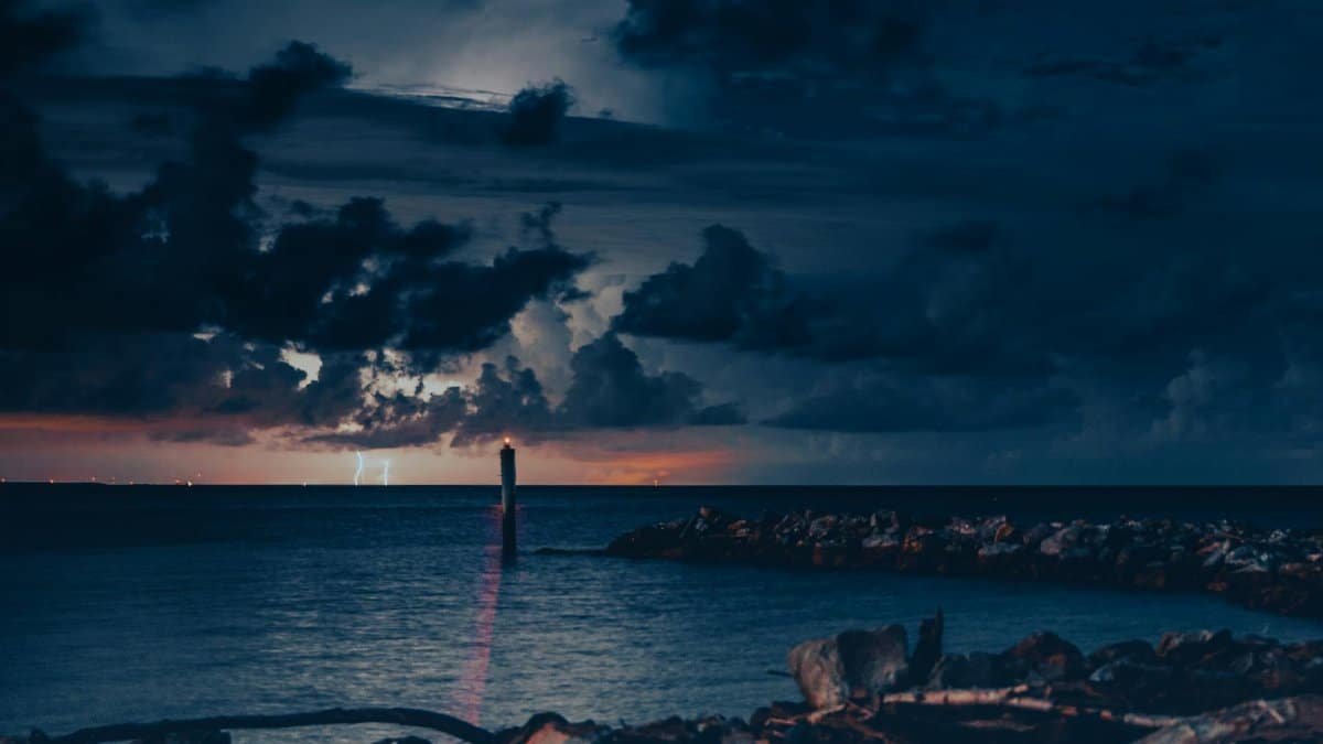 A dramatic night scene capturing lightning over the ocean at Dauphin Island, Alabama.