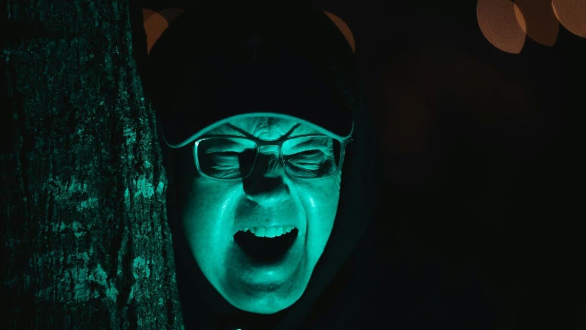 A dramatic green-lit portrait of a screaming man creates a spooky Halloween vibe.