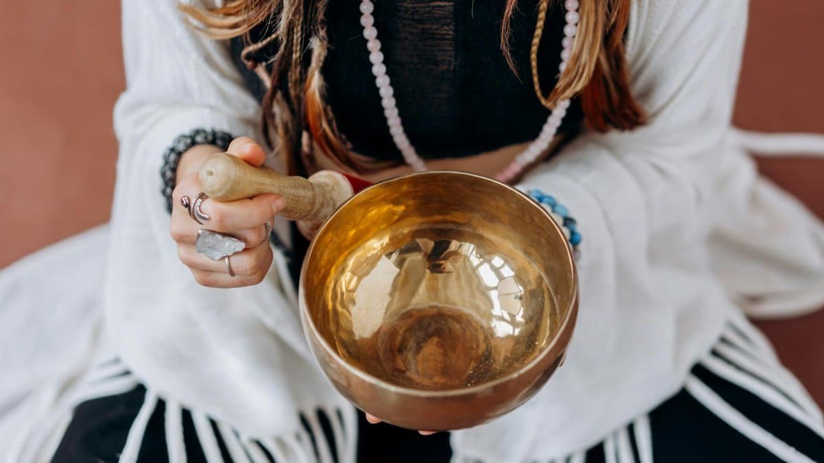 A woman holding a singing bowl, engaging in a peaceful meditation practice.