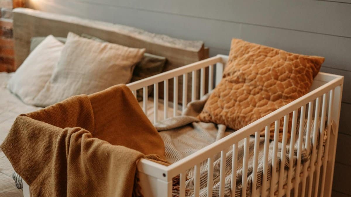 A cozy bedroom featuring a white crib with warm blankets and pillows, creating a comfortable ambiance.