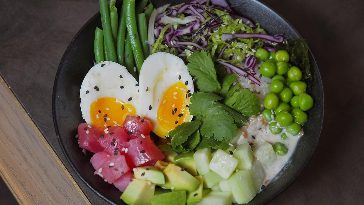 A delicious and colorful poke bowl featuring eggs, vegetables, and fresh produce, perfect for a healthy meal.