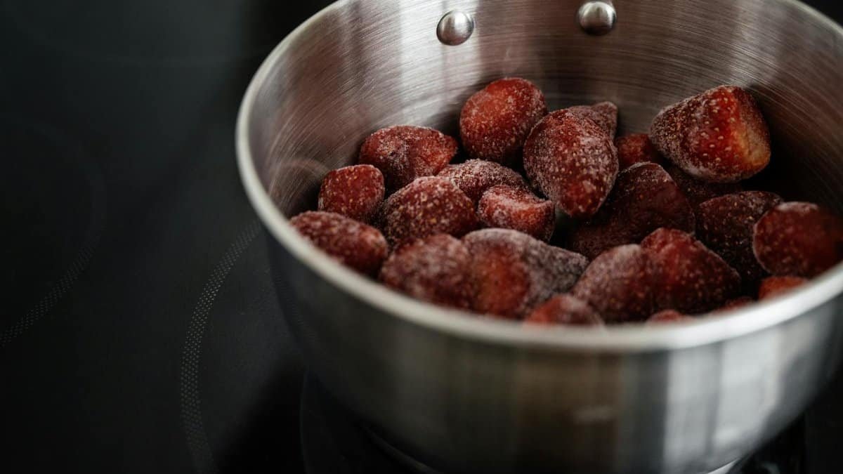 Close-up of frozen strawberries in a stainless steel pot, ready for cooking.