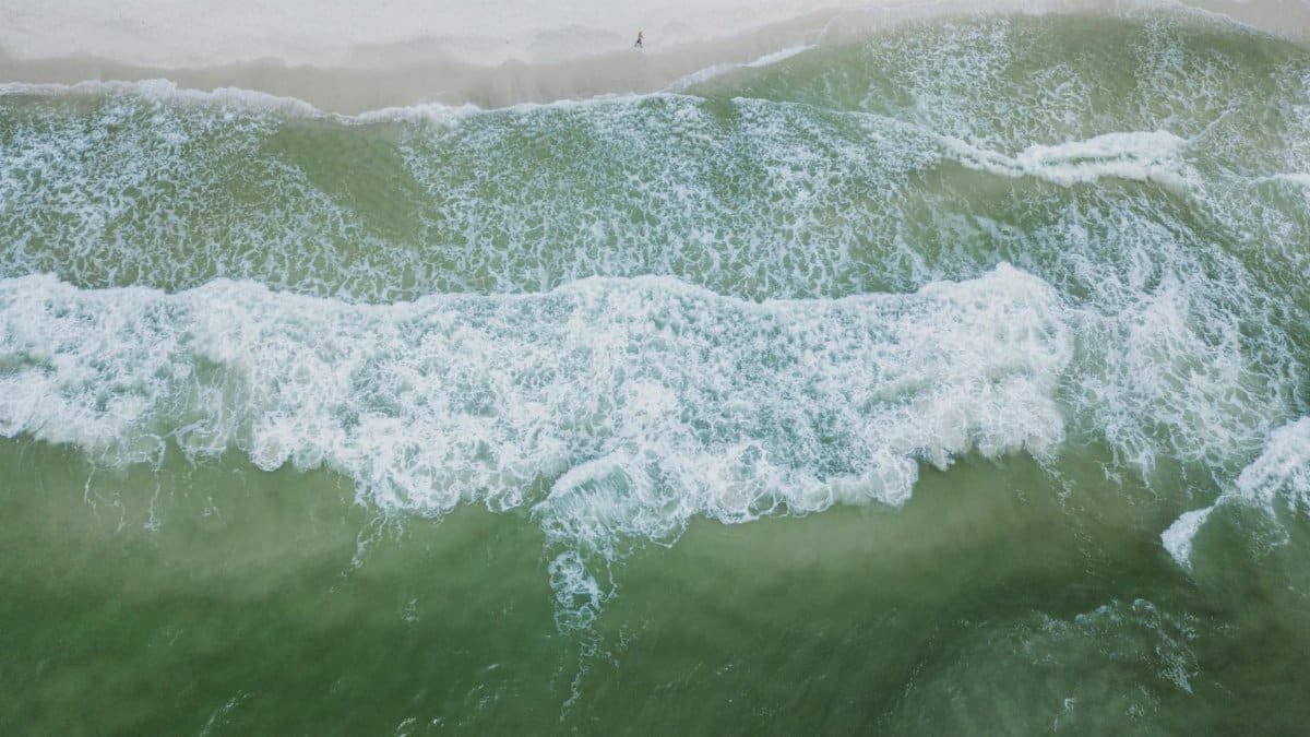 A breathtaking aerial view of ocean waves crashing onto the shores of Orange Beach, Alabama.