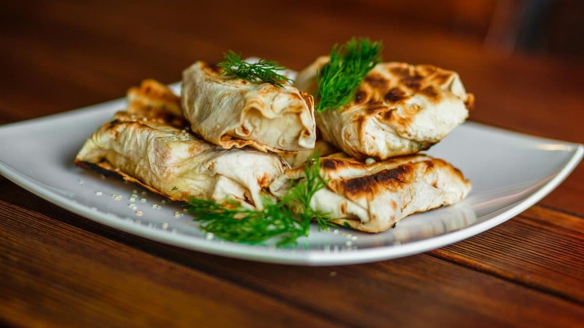 Delicious grilled wraps served on a plate with fresh dill garnish, perfect for a savory meal.