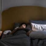 A man sleeping in a cozy bed with soft morning sunlight filtering in.