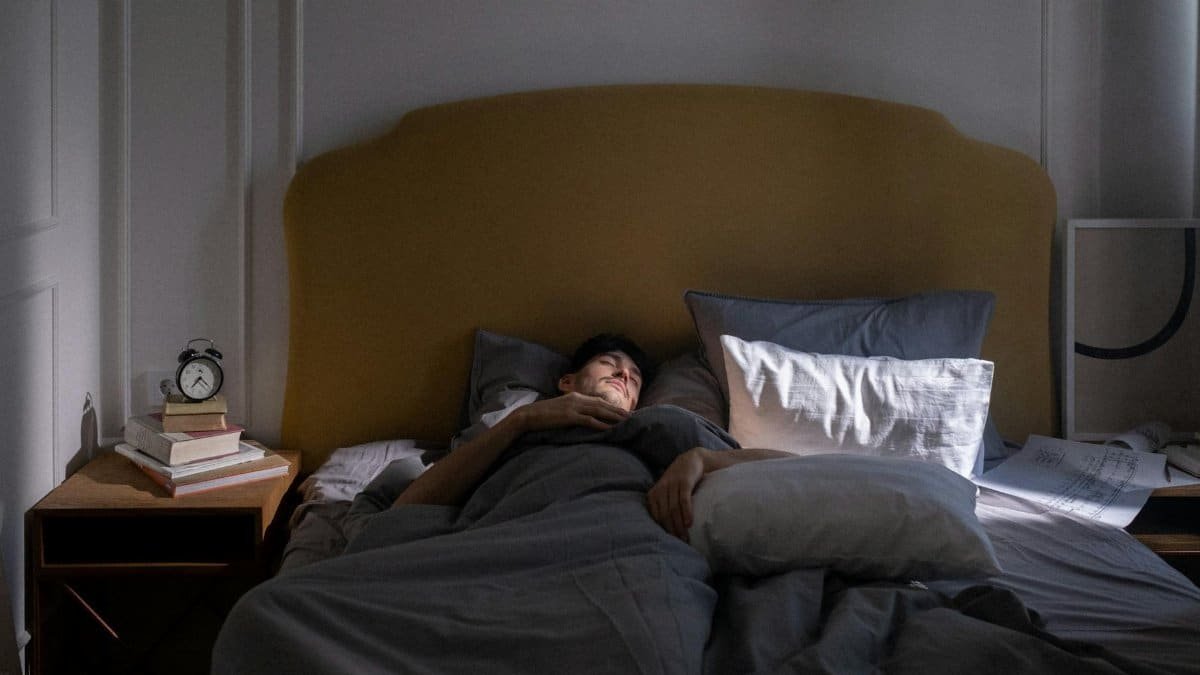 A man sleeping in a cozy bed with soft morning sunlight filtering in.