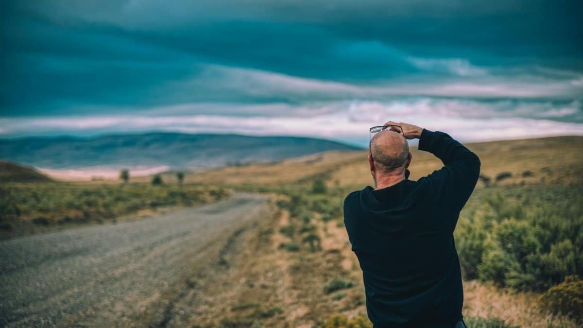 A person taking photos of the vast landscape in the Jordan Valley, Oregon, under a dramatic sky.