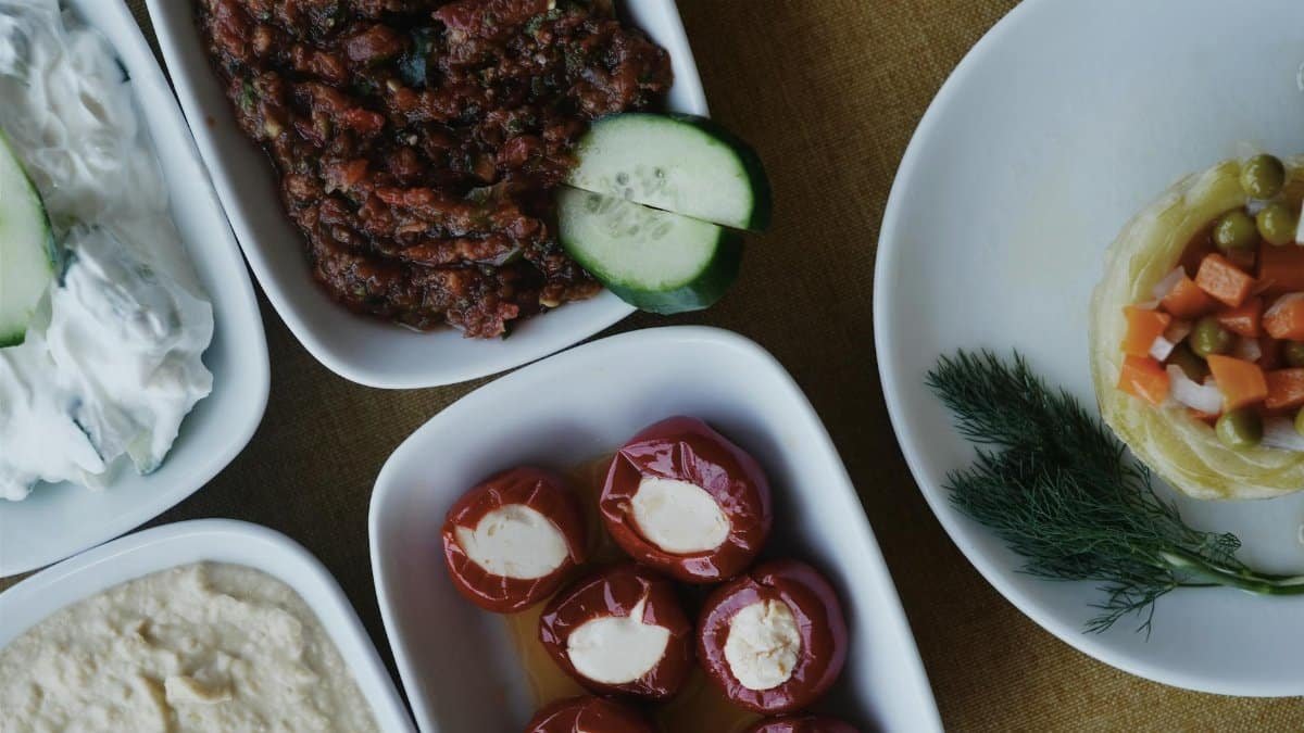 A selection of Mediterranean appetizers with cream cheese, roasted peppers, and fresh vegetables on plates.
