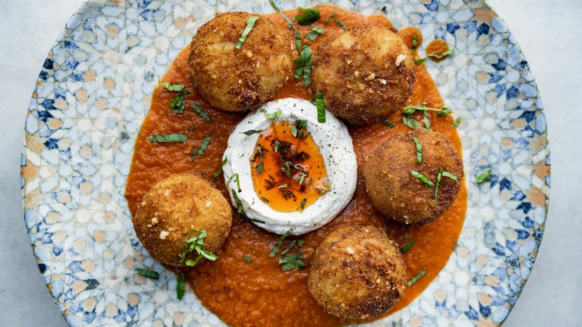 Crispy fried balls served on a rich tomato sauce, garnished with herbs.