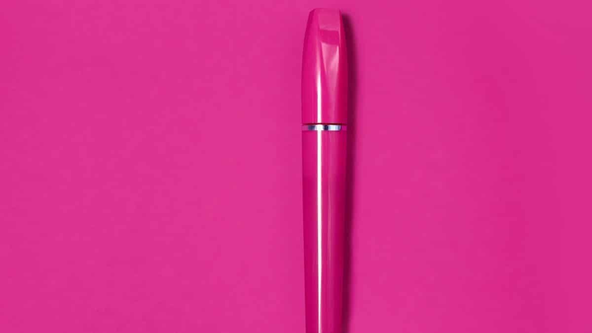 A striking pink mascara tube centered on a solid pink background, showcasing modern beauty packaging.