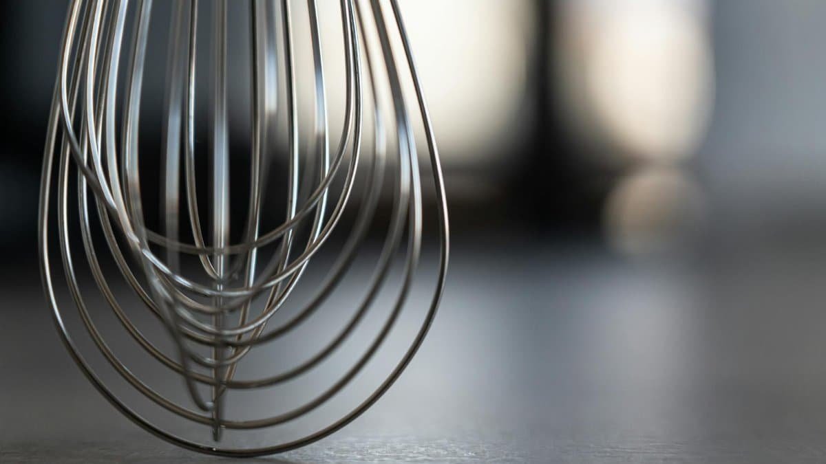 Close-up of a stainless steel whisk in a modern kitchen setting, showcasing sleek design.