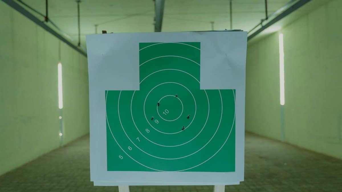 A green circle target with bullet holes at an indoor shooting range, ideal for practice visuals.