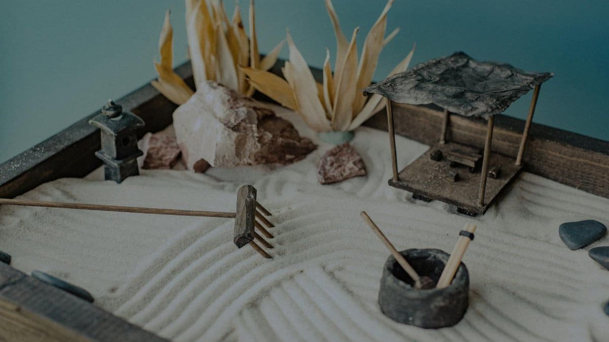 A calming miniature Zen garden featuring sand, stones, and decorative elements like a pavilion and lantern.
