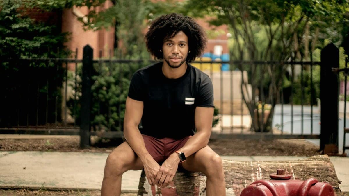 A stylish man with curly hair sitting outdoors on a bench in Chicago.