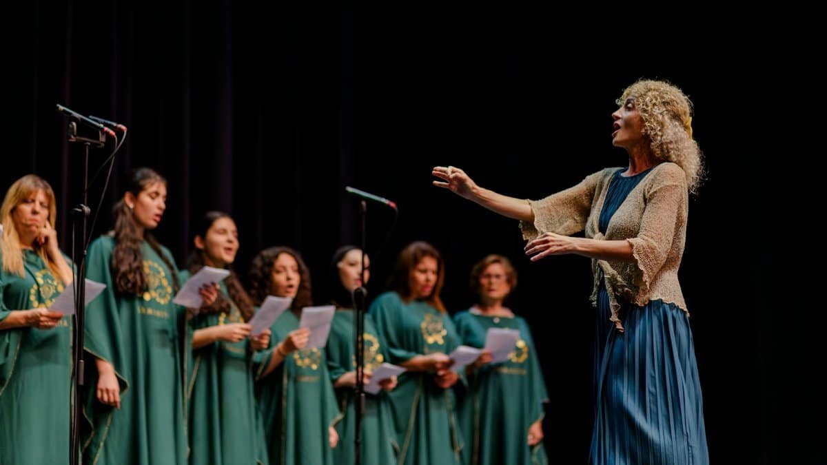 A choir performing on stage led by a conductor, highlighting teamwork and harmony.