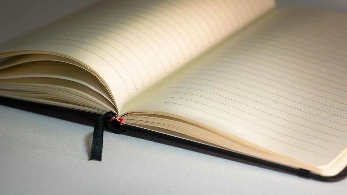 Open lined notebook with a black ribbon on a desk, ready for writing.
