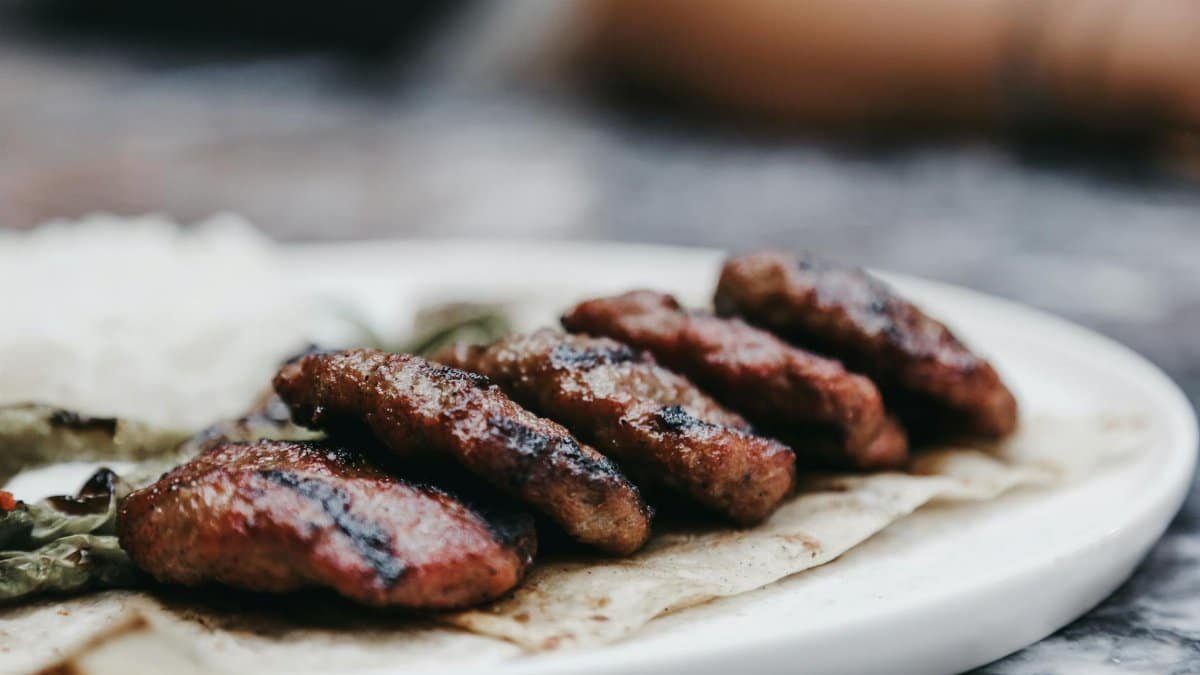 Close-up of grilled beef patties served on a tortilla with rice and vegetables, showcasing a delicious meal.
