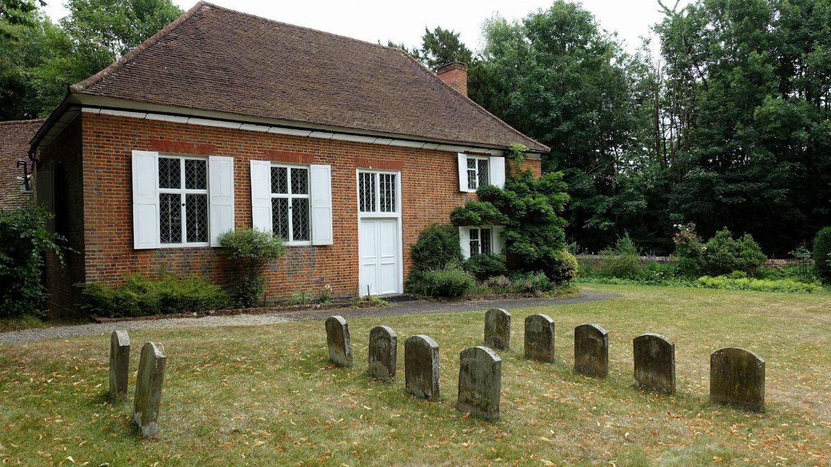 Quaint historical building with old gravestones in a peaceful churchyard setting.