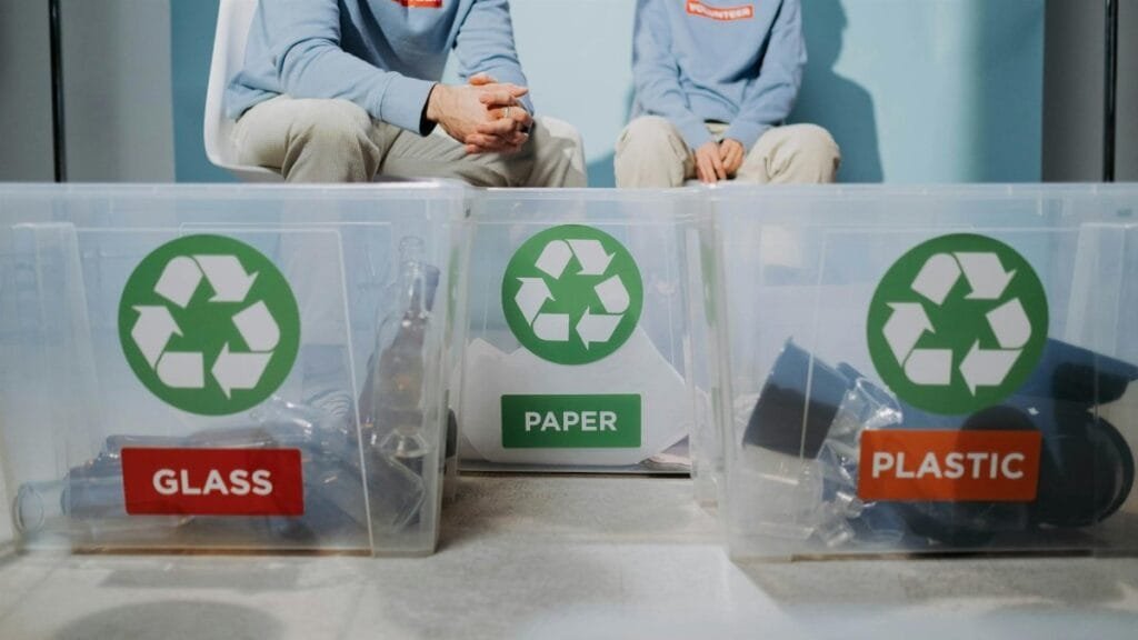 Volunteers organize recyclables into glass, paper, and plastic bins to promote eco-friendly practices.