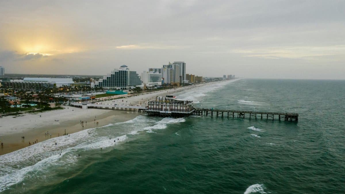 A stunning aerial view of Daytona Beach's pier and coastline at sunset with vibrant ocean waves.