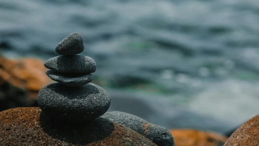 Close-up of stacked stones embodying peace and balance by a calm body of water.