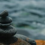 Close-up of stacked stones embodying peace and balance by a calm body of water.
