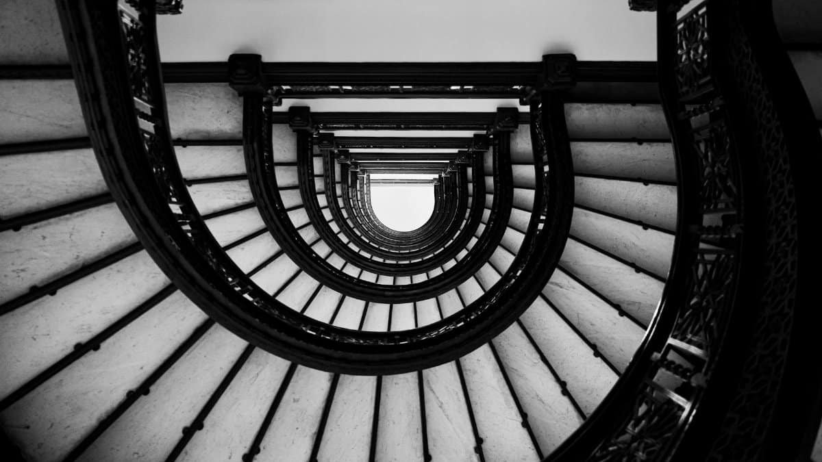 A dramatic black and white view of a spiral staircase with intricate handrails, capturing architectural beauty.