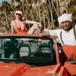 A playful Santa-themed scene with a convertible car by the beach.