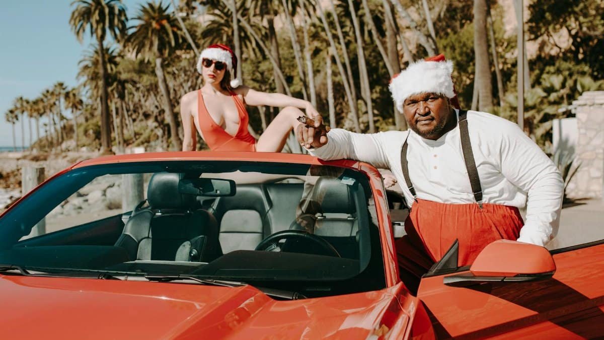 A playful Santa-themed scene with a convertible car by the beach.