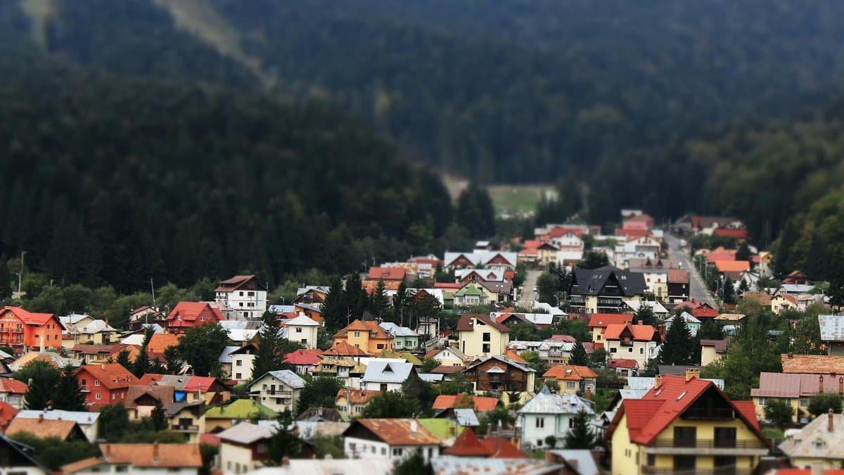 A vibrant village nestled in a lush green valley surrounded by dense forest.