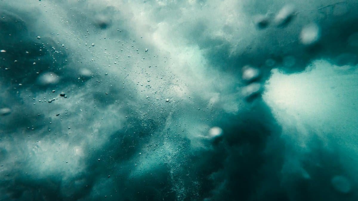 Dynamic underwater scene capturing bubbles and turbulence in a vibrant and abstract blue environment.