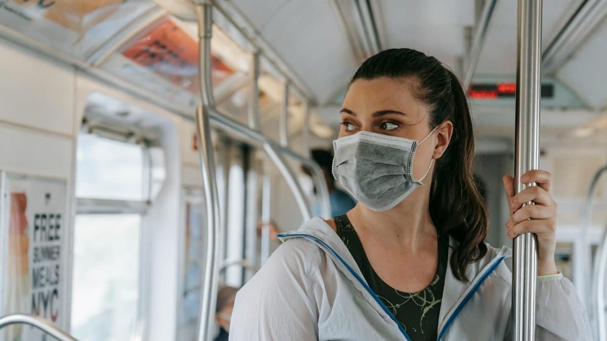 A woman wearing a face mask rides the New York City subway, emphasizing pandemic safety trends.