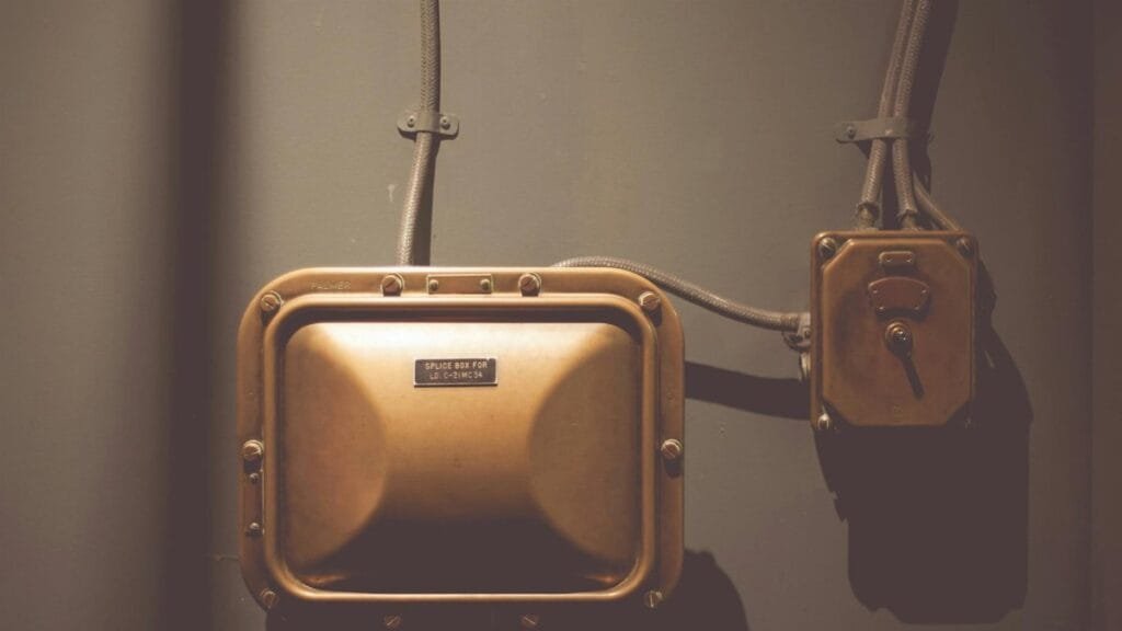 Industrial electrical control box with vintage design and copper finish on a wall.