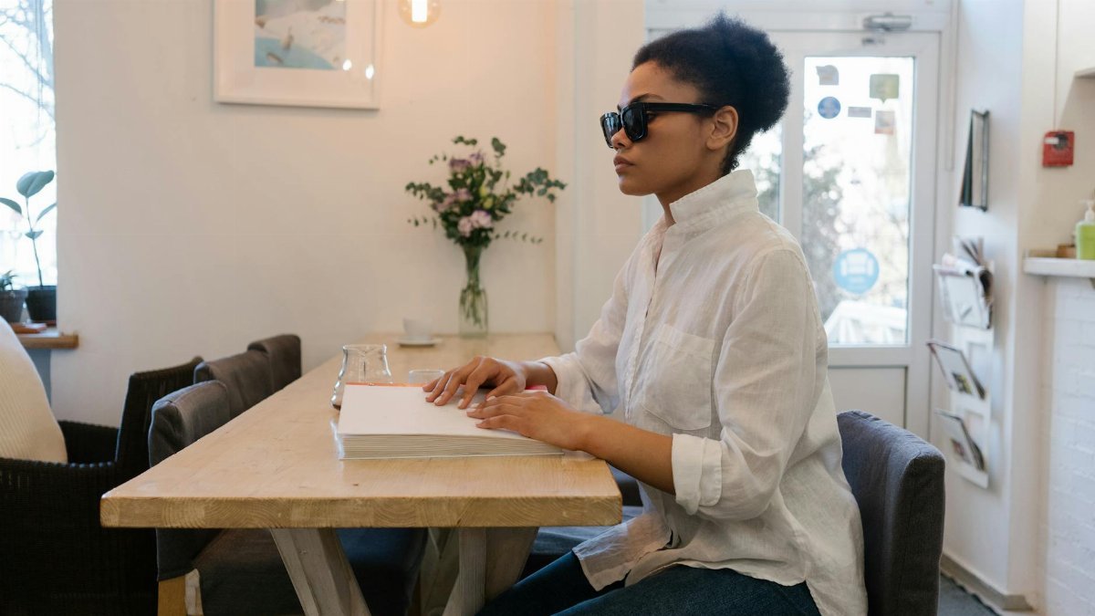 African American woman using Braille in a cozy cafe setting.