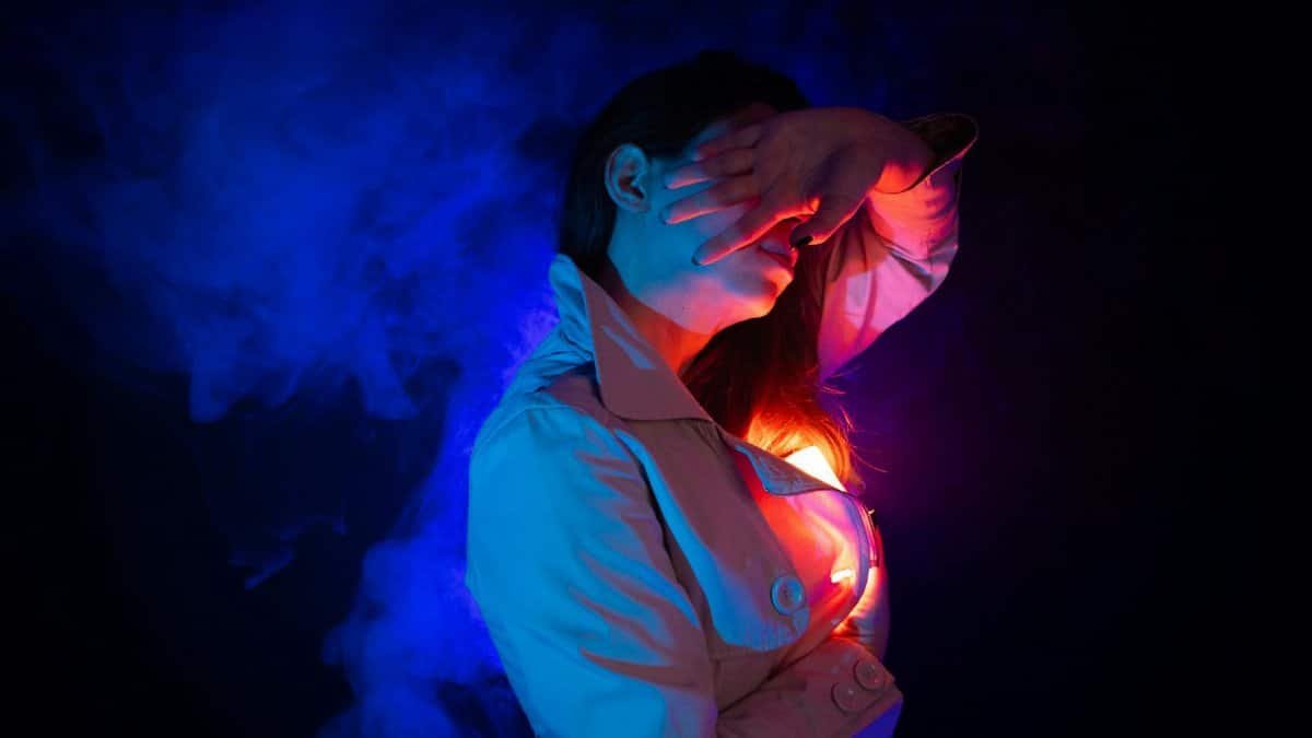 Stylized portrait of a woman with vibrant colored lighting and smoke, creating a cinematic effect.