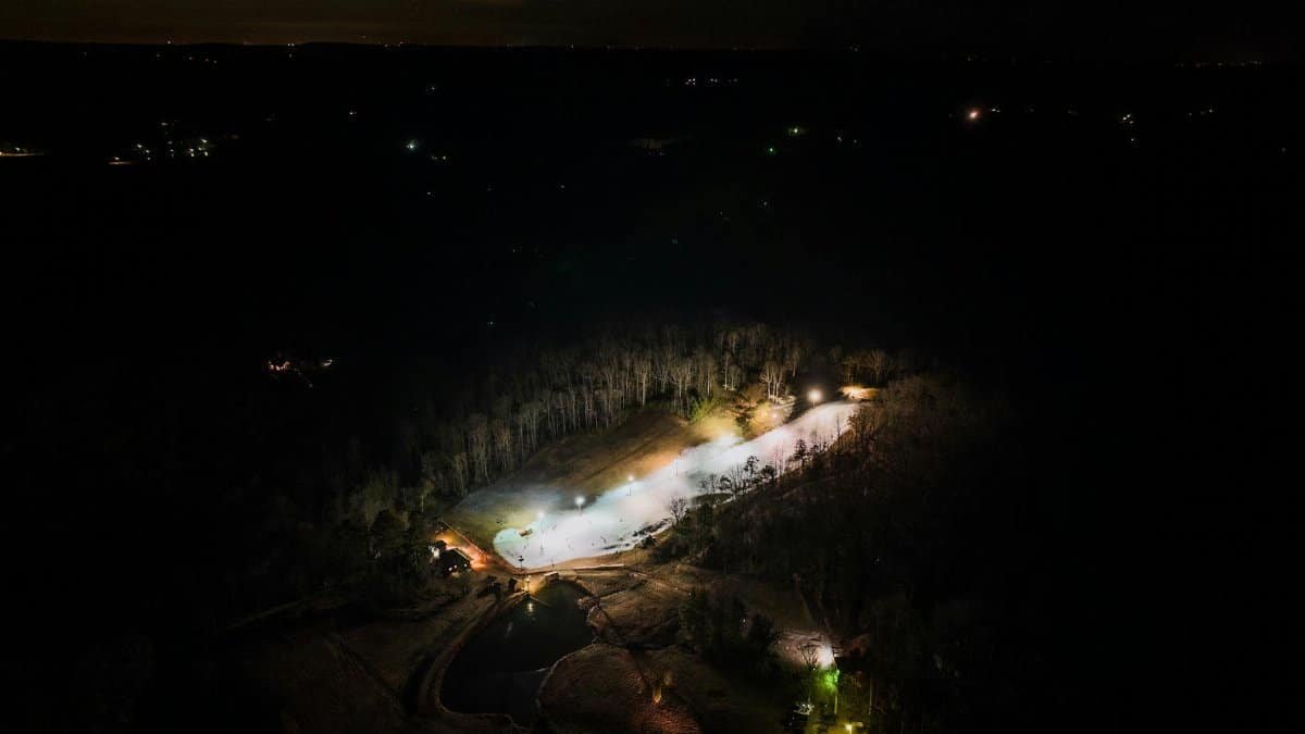Dramatic aerial night view of a ski resort amid Alabama's forests, beautifully illuminated.