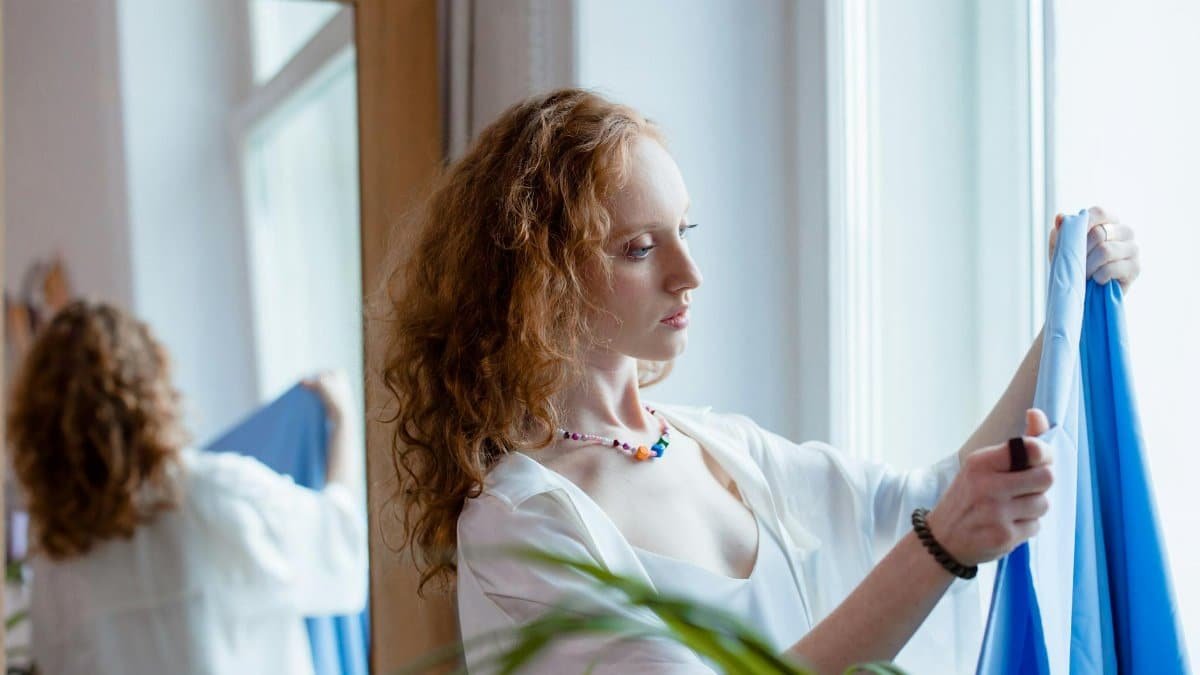 Woman fashion designer selecting fabric at home, reflecting creativity and style.