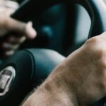 Hands firmly gripping a car steering wheel, ready to drive.