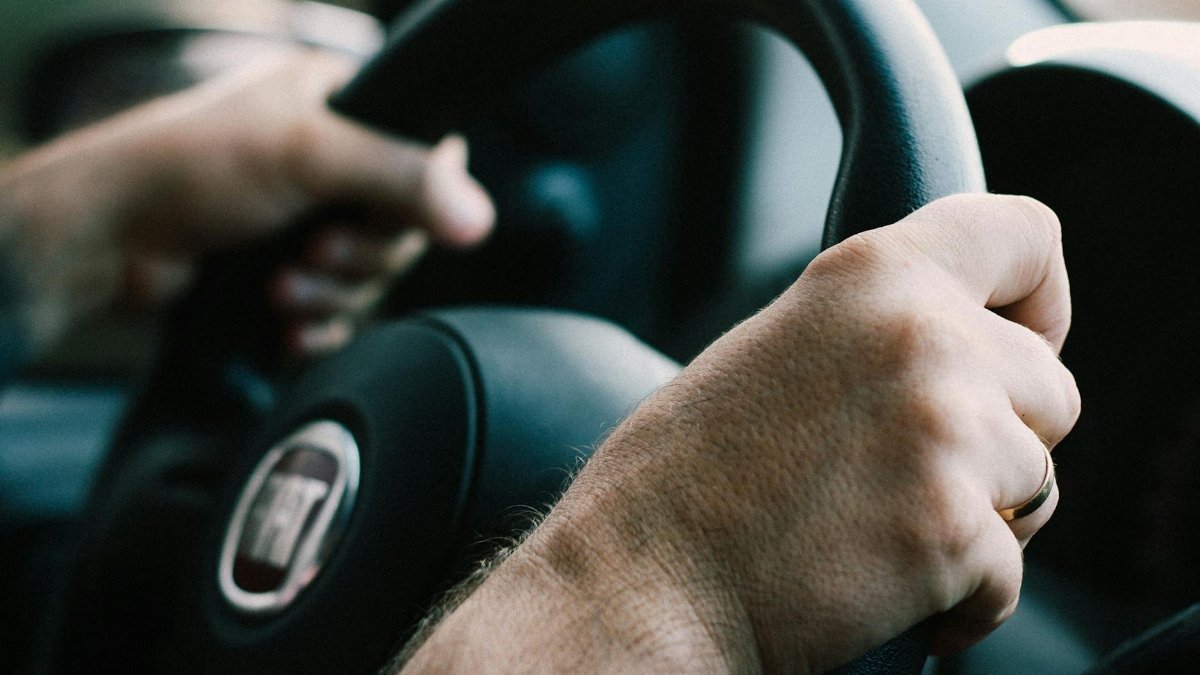 Hands firmly gripping a car steering wheel, ready to drive.